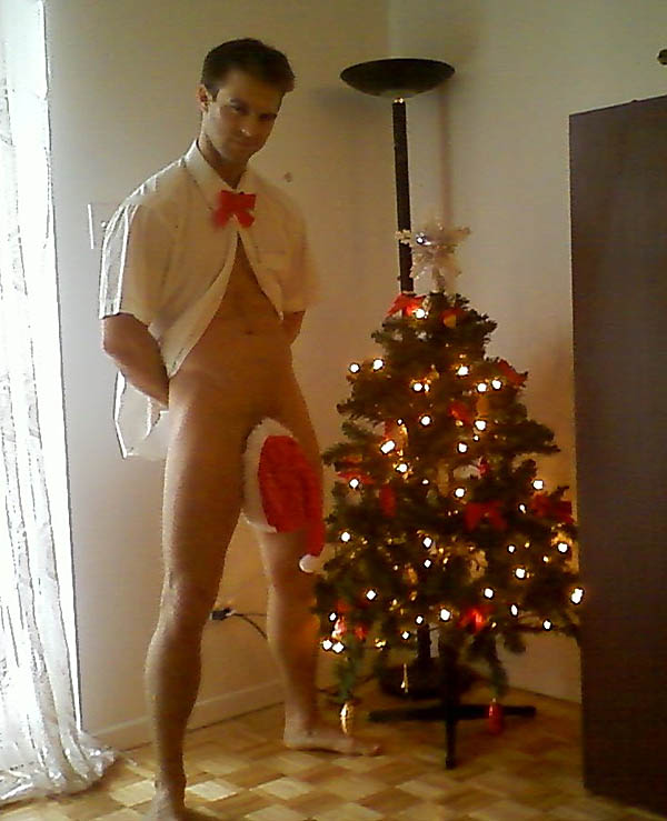 Gay porn Star Gabriel Clark by the Christmas tree wearing only a hat.